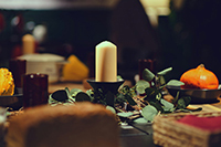 unlit candle on an nighttime elegant table setting including leaves and bread