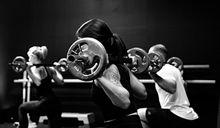 men and women lifting barbells in fitness class